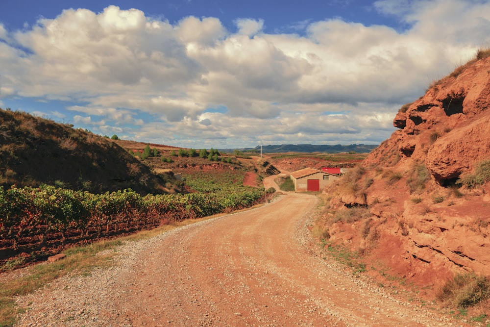 a dirt road with a red building in the distance