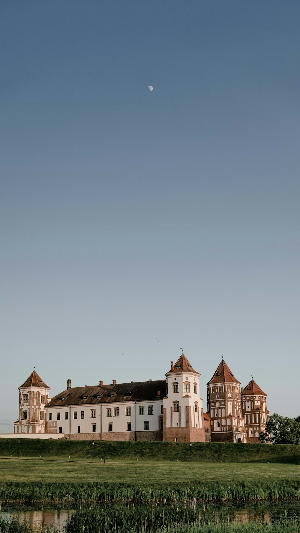 a large white building sitting on top of a lush green field