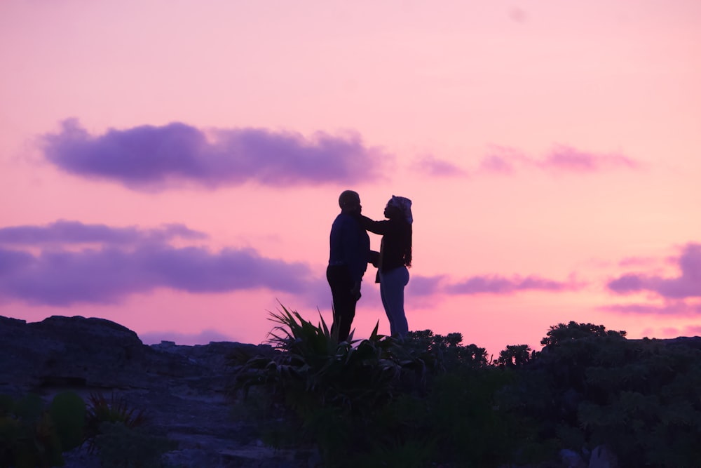 a couple of people standing on top of a hill