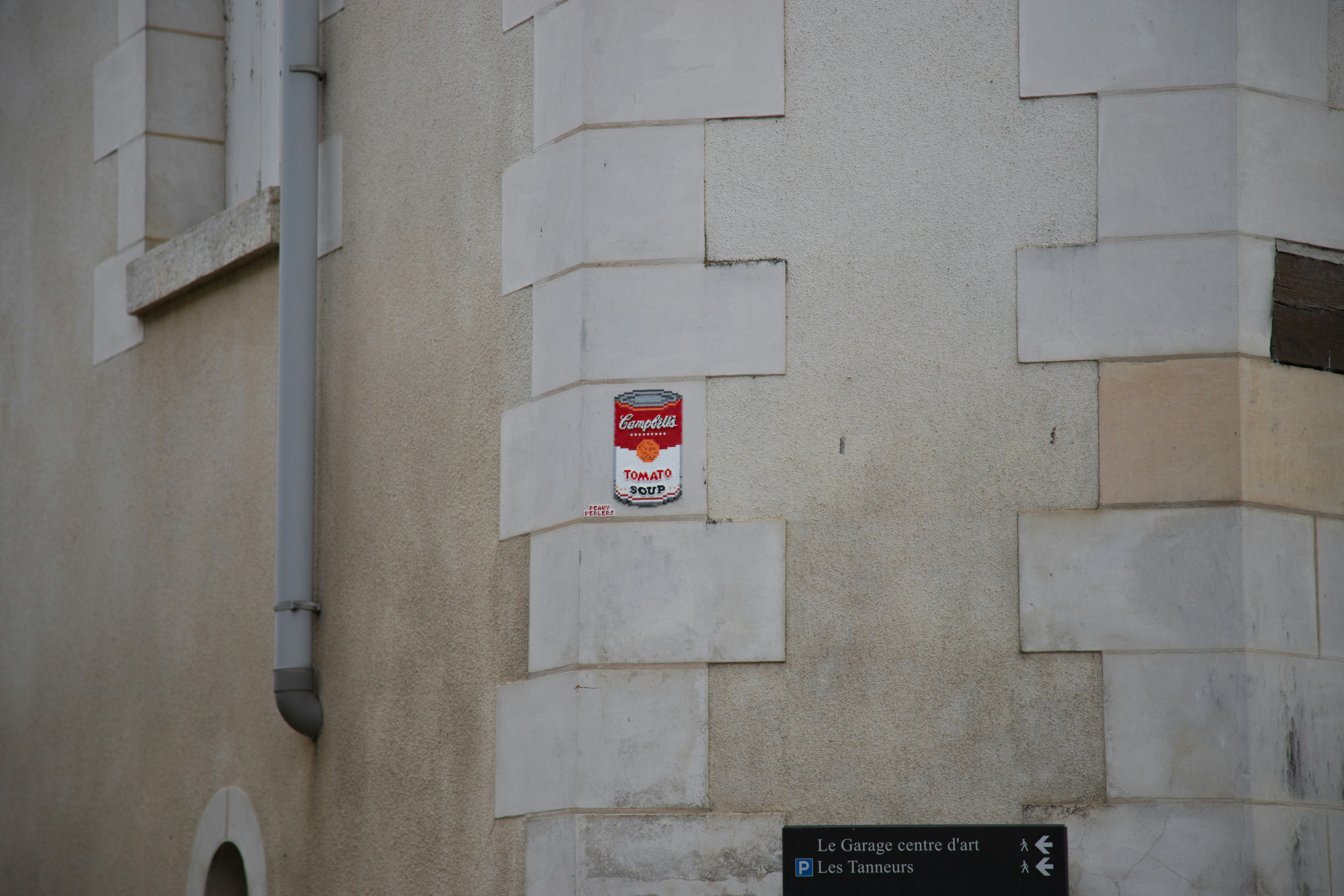 eine Dose Tomatensuppe an einer Wand neben einem Straßenschild