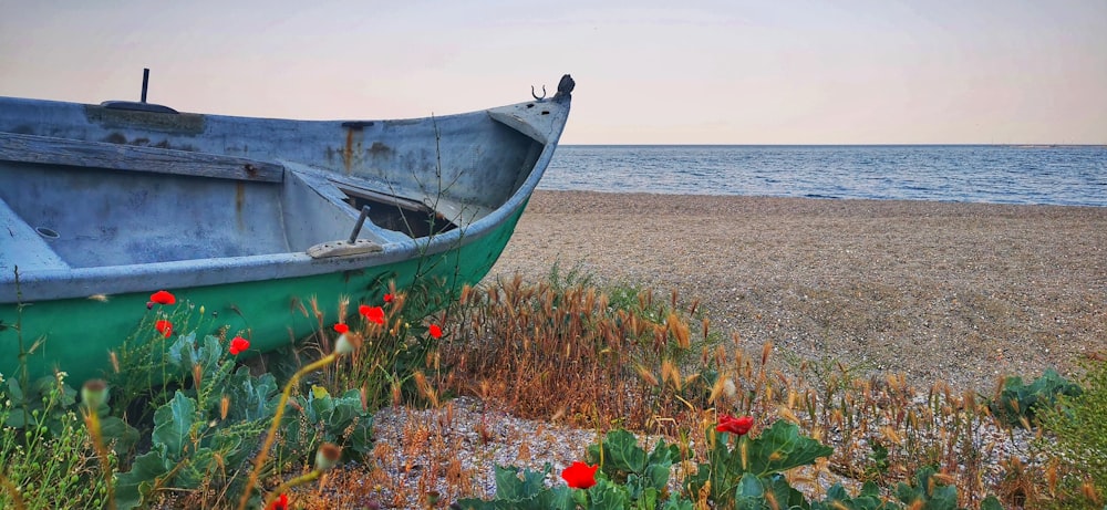 a green boat sitting on top of a [UNK] beach