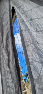 Close-up of mesh balcony curtains gently swaying in a soft breeze with sunlight filtering through.