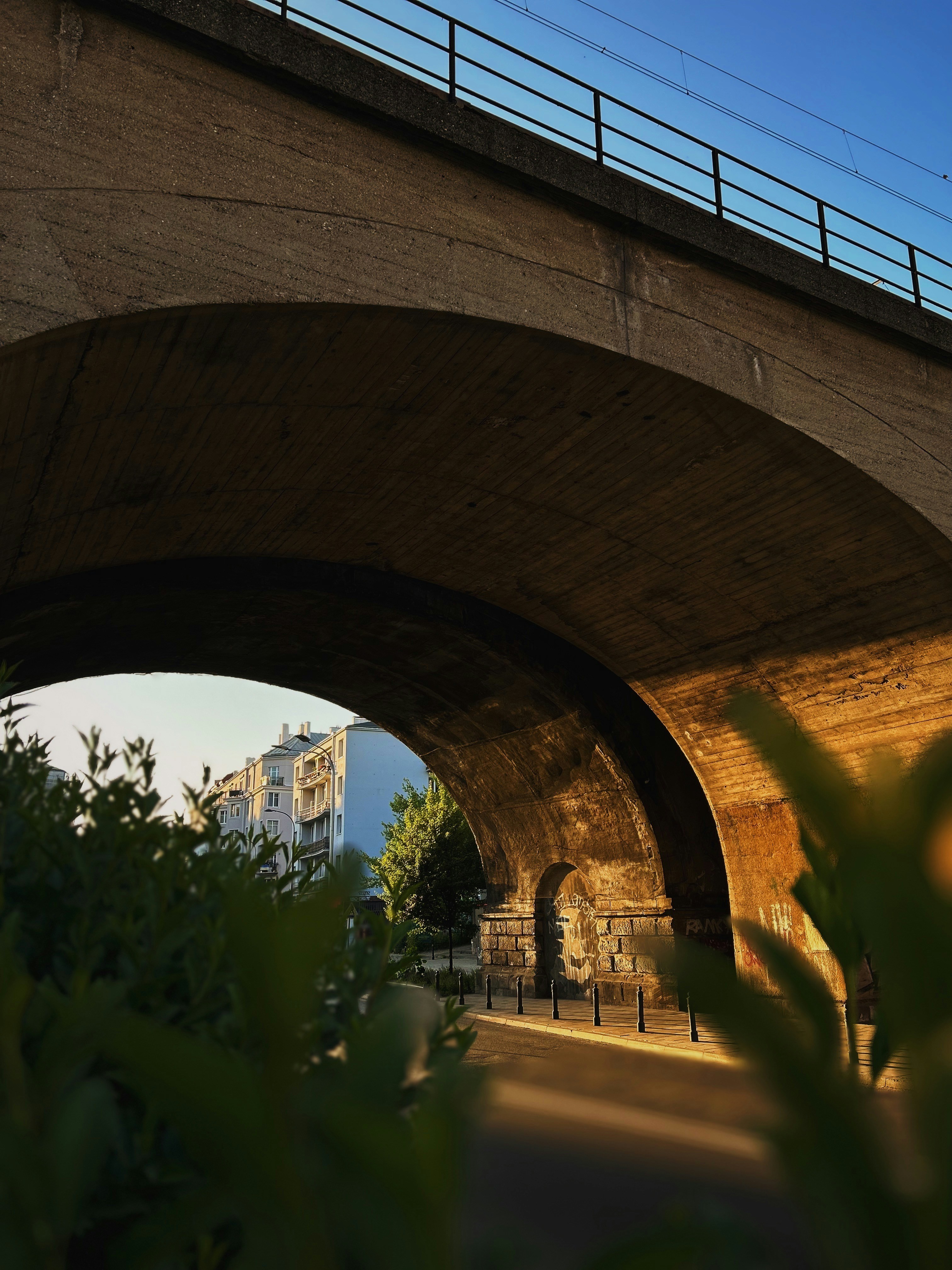 a bridge over a street with a clock tower in the background