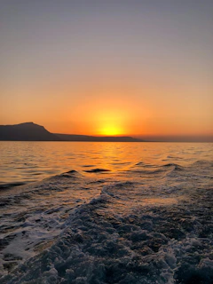 A serene sunrise over a calm ocean horizon with gentle waves.