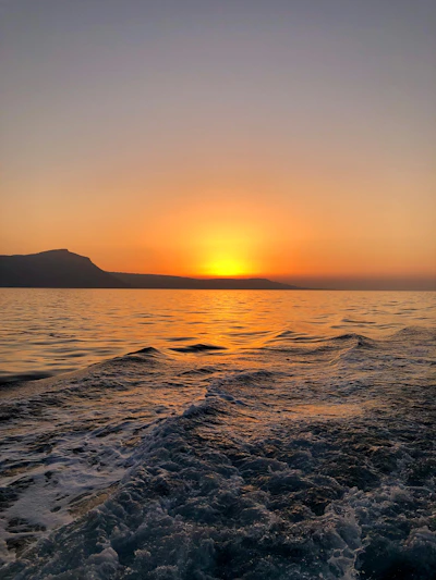 A serene sunrise over a calm ocean horizon with gentle waves.