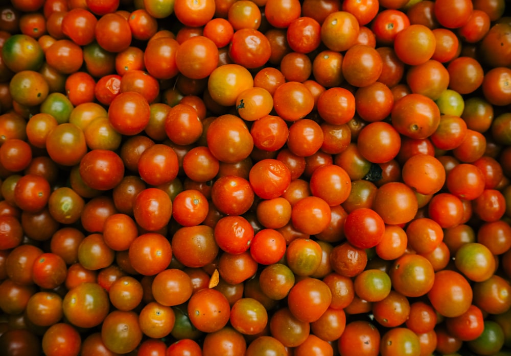 a large pile of orange and green tomatoes