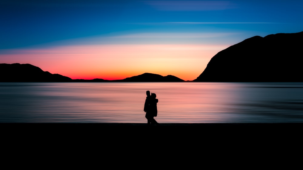 uma pessoa em pé em uma praia ao pôr do sol