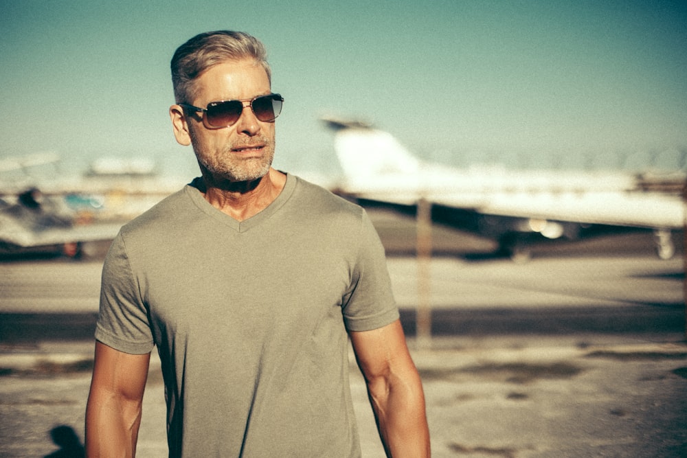 a man wearing sunglasses standing in front of an airplane