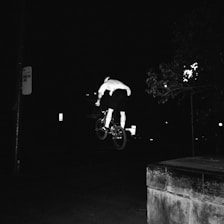 A dynamic photo of Alexandre racing on his BMX bike against a dark background.
