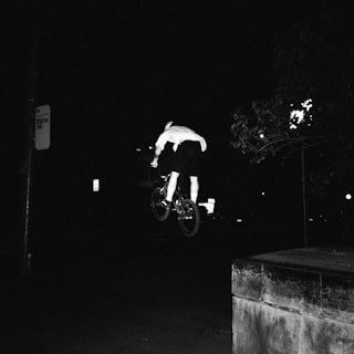 Alexandre executing a dynamic BMX race jump against a dark background