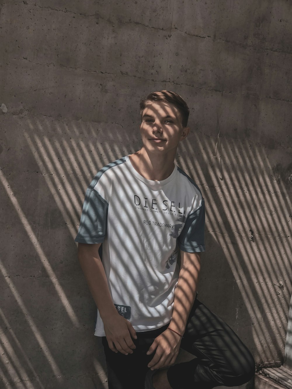 a young man sitting against a [UNK] wall