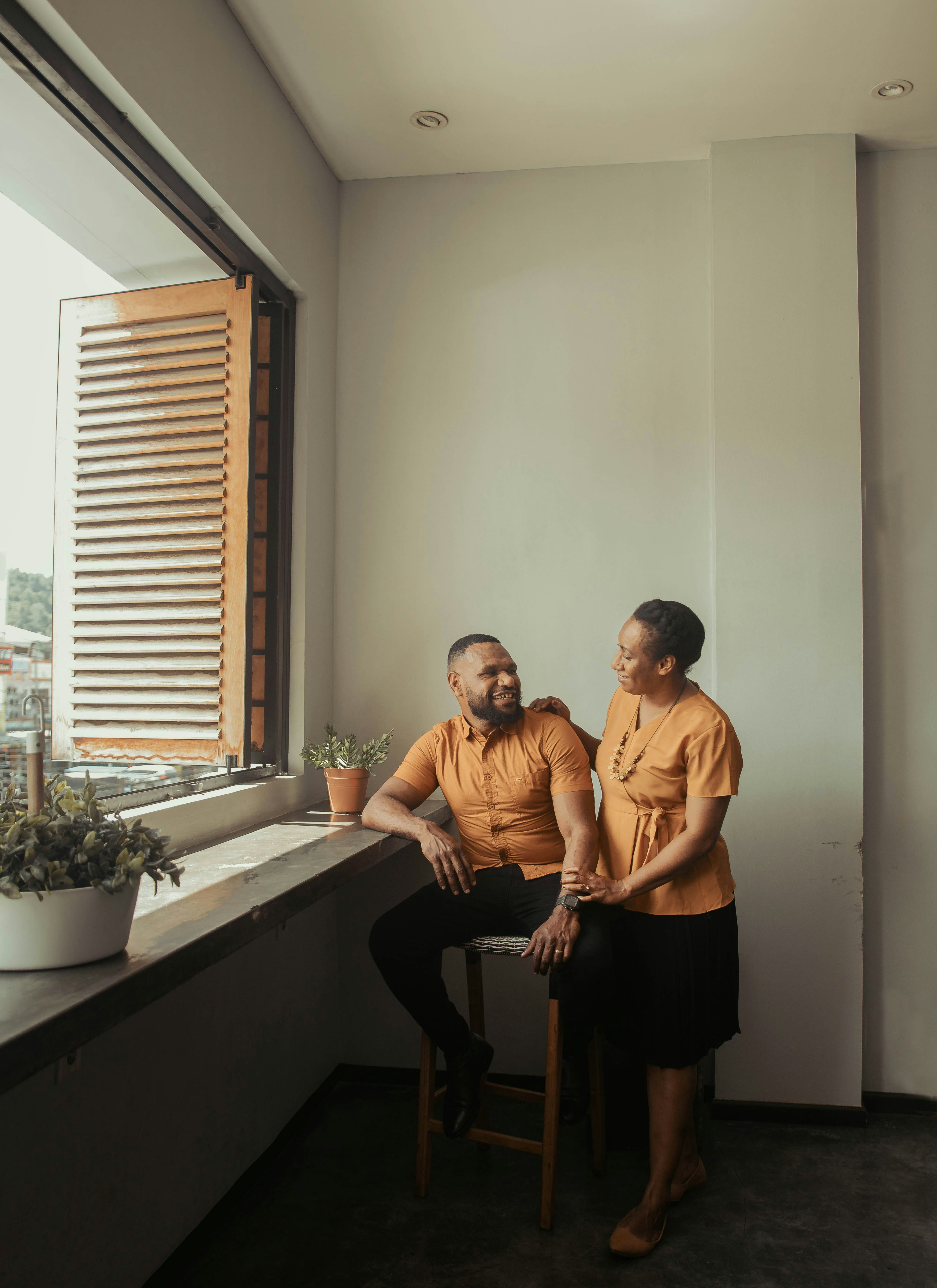 a man and a woman sitting on a window [UNK]ll