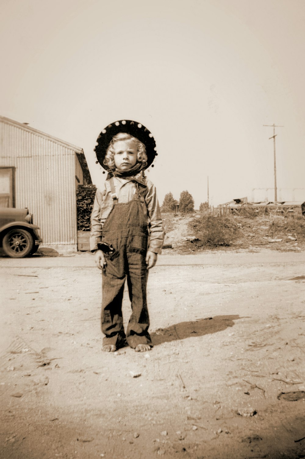a young boy wearing a cowboy hat and overalls