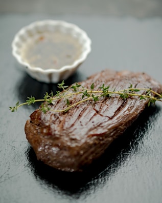 Close-up of a perfectly seared steak garnished with herbs and a drizzle of sauce.