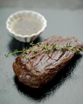 Close-up of a sleek kitchen thermometer next to a perfectly cooked steak on a rustic wooden table.