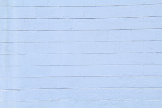 A light blue concrete block wall with visible horizontal and vertical seams. The surface appears smooth with slight textures and imperfections.
