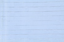 A light blue concrete block wall with visible horizontal and vertical seams. The surface appears smooth with slight textures and imperfections.