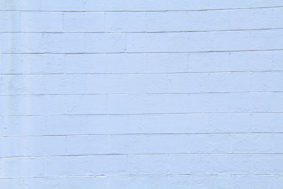 A light blue concrete block wall with visible horizontal and vertical seams. The surface appears smooth with slight textures and imperfections.