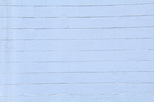 A light blue concrete block wall with visible horizontal and vertical seams. The surface appears smooth with slight textures and imperfections.