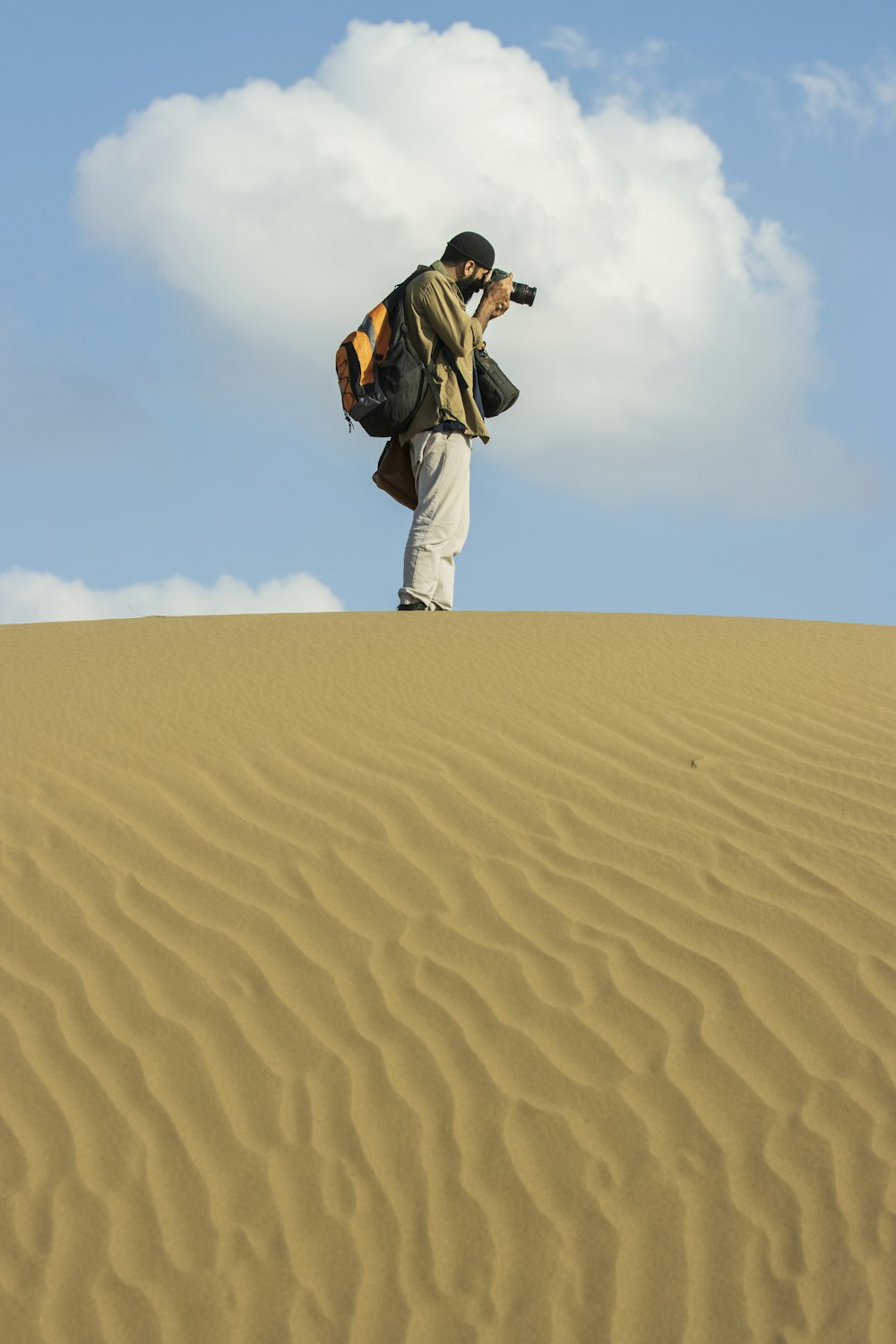 Un homme debout au sommet d’une dune de sable