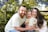 A smiling family embracing each other outdoors on a bright day.