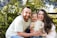 A happy family standing outside a beautiful villa surrounded by lush greenery.