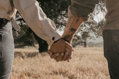a man and a woman holding hands in a field