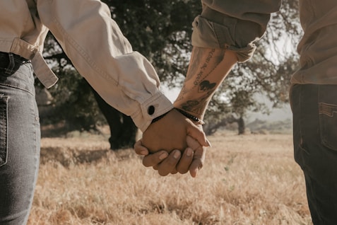 a man and a woman holding hands in a field