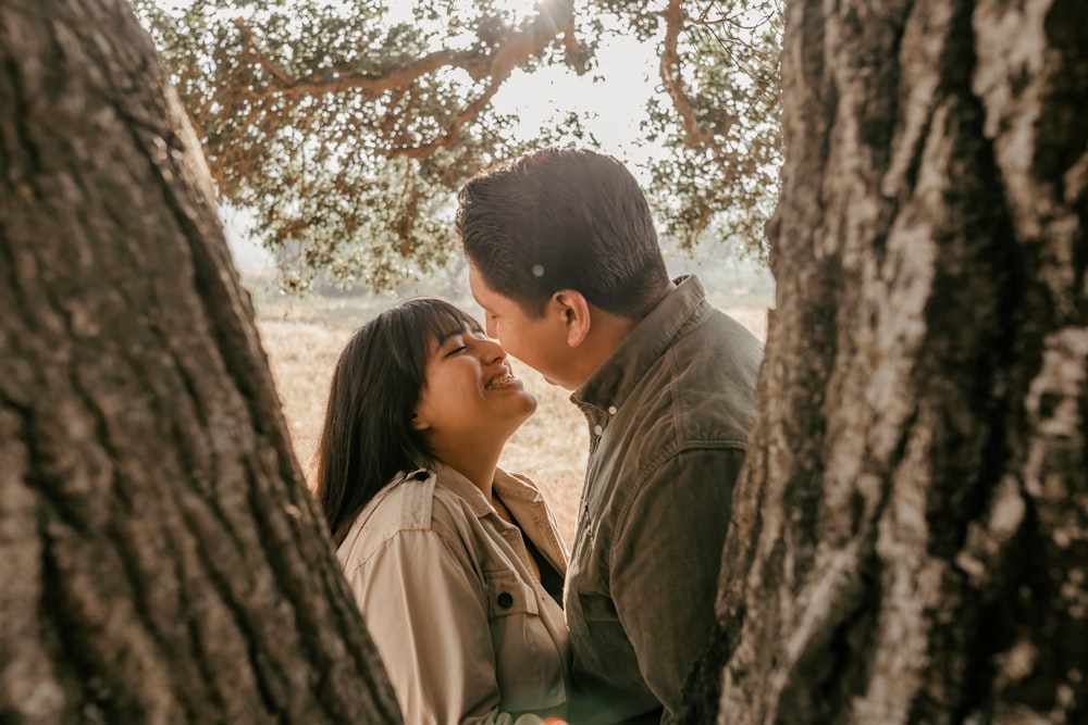 a man and a woman standing next to each other under a tree