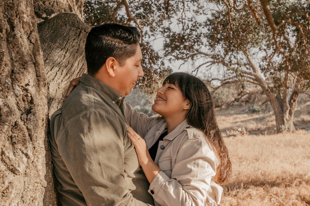 a man and a woman standing next to a tree