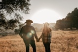 a man and woman holding hands in a field