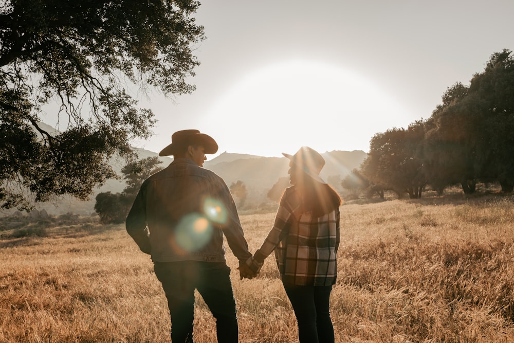 a man and woman holding hands in a field