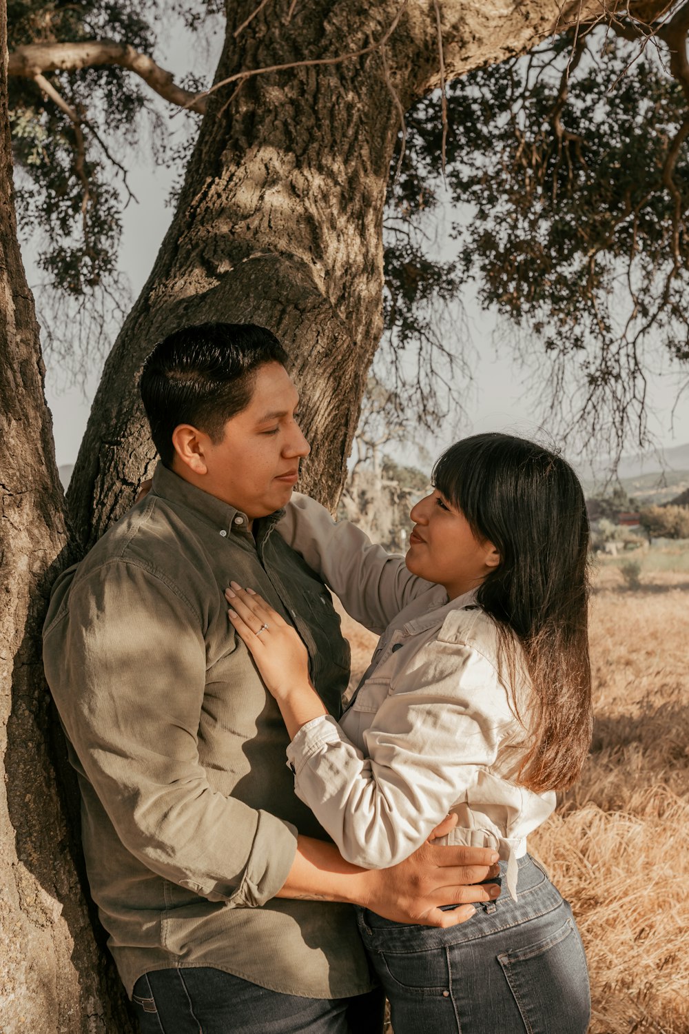 a man and a woman standing next to a tree