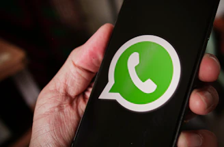 A friendly person holding a smartphone with WhatsApp open, ready to chat.