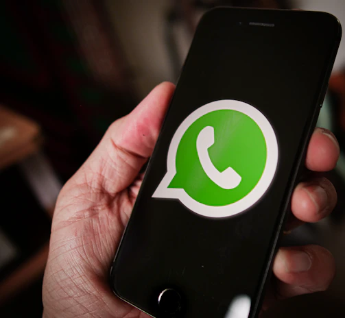 A friendly person holding a smartphone with WhatsApp open, ready to chat.