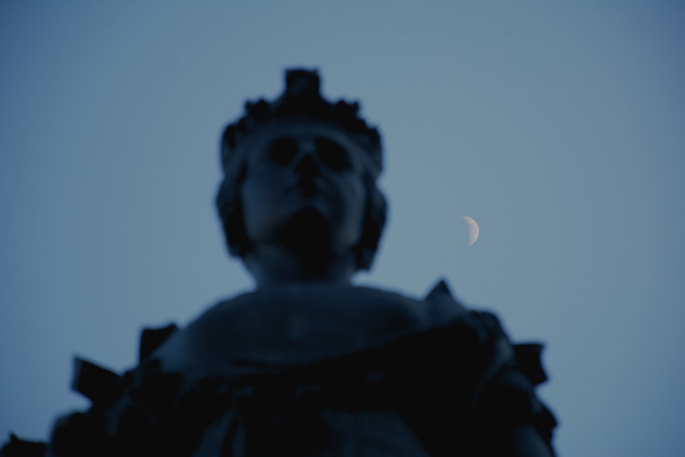 Una estatua con una media luna en el fondo