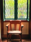 Close-up of a handcrafted wooden chair beside a window with forest views.