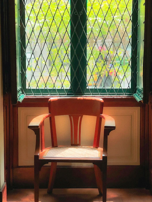A cozy seat cushion on a wooden chair by a sunny window