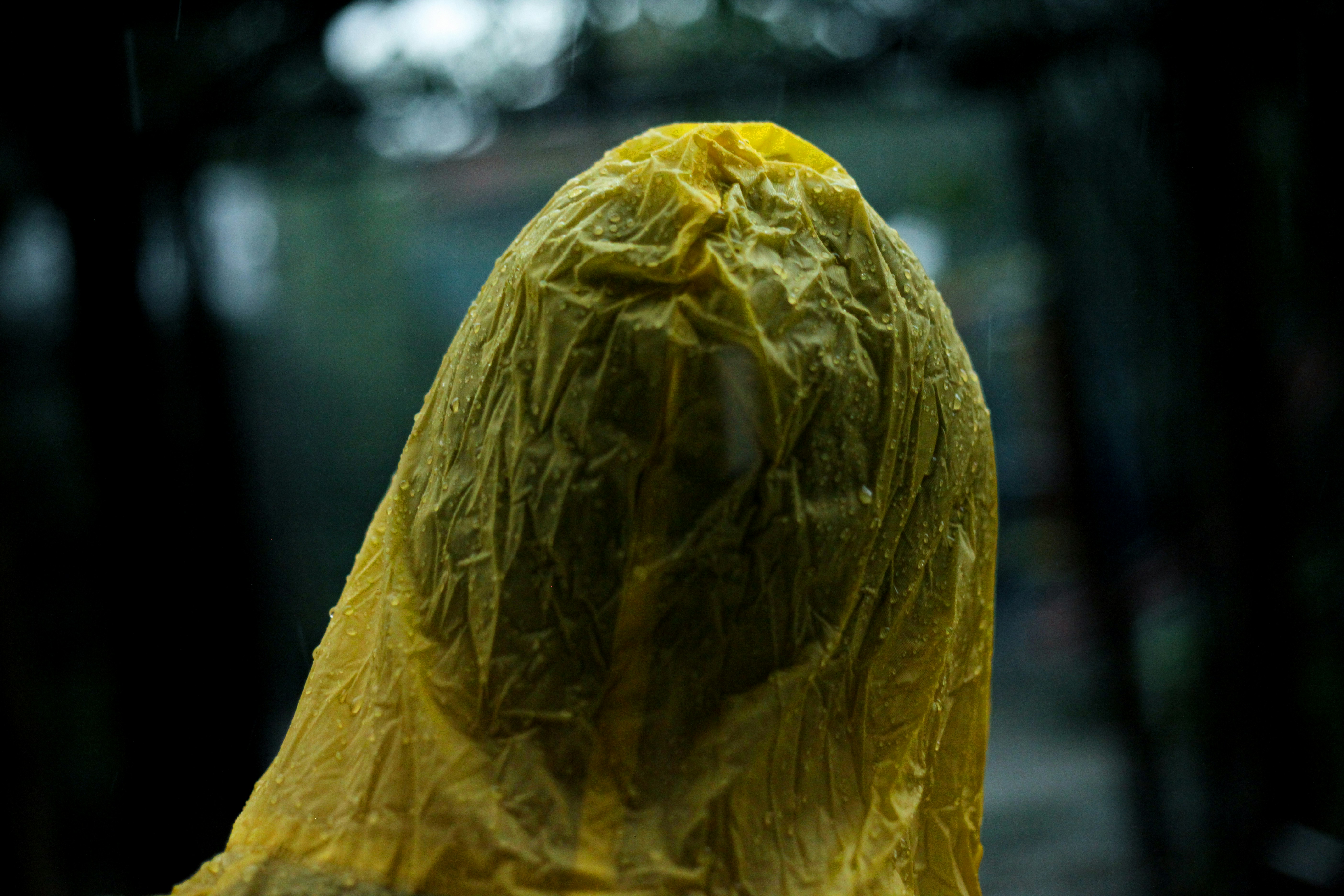 a person in a yellow raincoat with a plastic bag on their head