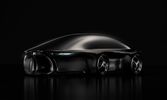A sleek, futuristic black car with smooth, aerodynamic curves. The vehicle appears to be a concept car, reflecting a minimalist and cutting-edge design aesthetic. The image uses dramatic lighting that highlights the car's streamlined shape and glossy finish on a dark background.