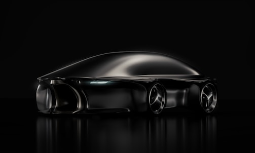 A sleek, futuristic black car with smooth, aerodynamic curves. The vehicle appears to be a concept car, reflecting a minimalist and cutting-edge design aesthetic. The image uses dramatic lighting that highlights the car's streamlined shape and glossy finish on a dark background.