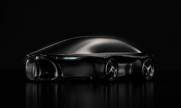 A sleek, futuristic black car with smooth, aerodynamic curves. The vehicle appears to be a concept car, reflecting a minimalist and cutting-edge design aesthetic. The image uses dramatic lighting that highlights the car's streamlined shape and glossy finish on a dark background.