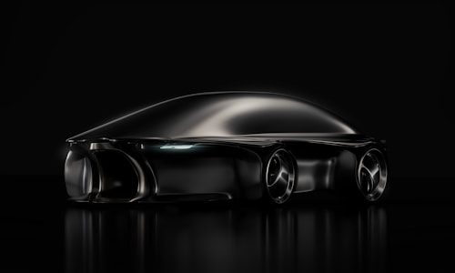 A sleek, futuristic black car with smooth, aerodynamic curves. The vehicle appears to be a concept car, reflecting a minimalist and cutting-edge design aesthetic. The image uses dramatic lighting that highlights the car's streamlined shape and glossy finish on a dark background.