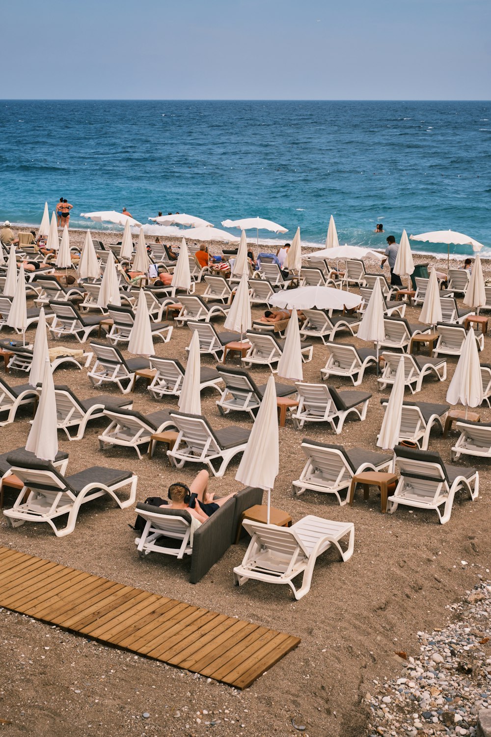 um monte de cadeiras de gramado e guarda-sóis em uma praia