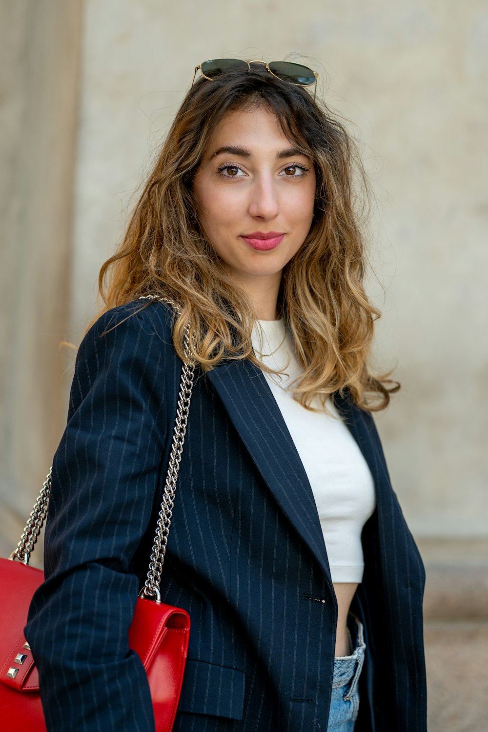 a woman wearing a suit and holding a red purse