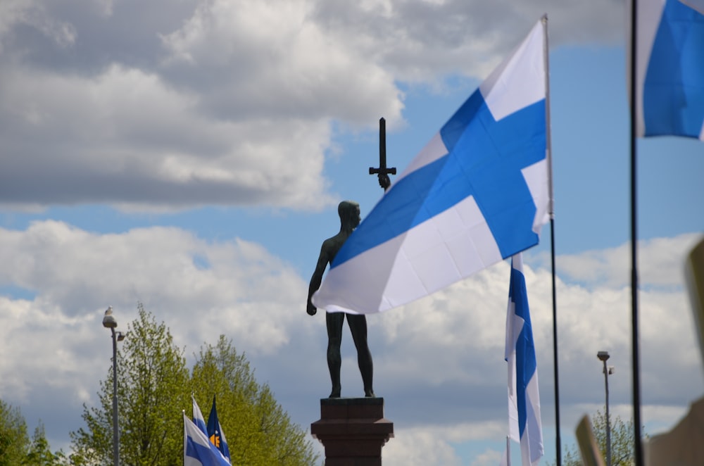 une statue d’une personne tenant une croix et un drapeau