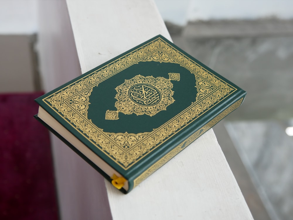 a green and gold book sitting on top of a white table