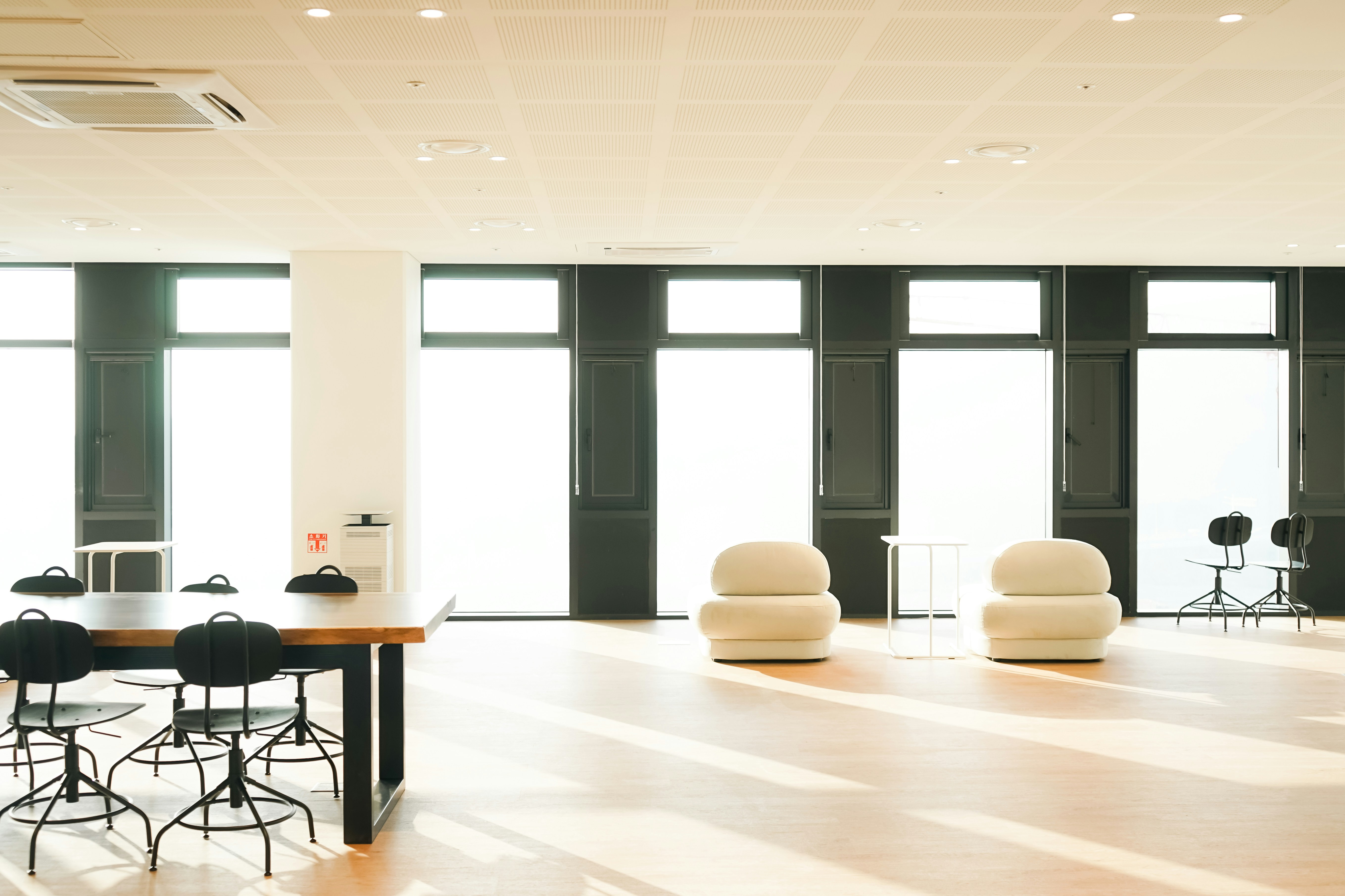 glass office building interior with empty boardroom table and executive seating