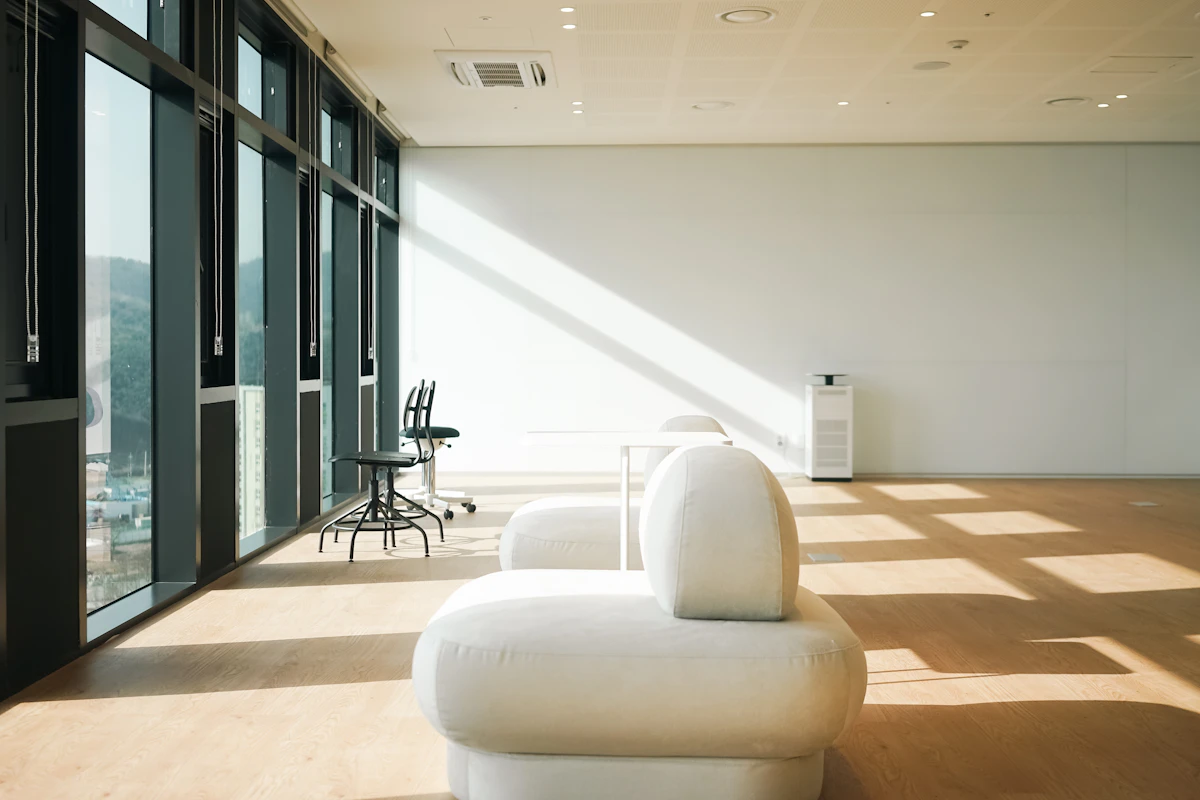 A sunlit office with a soft bouclé lounge chair and pale oak floor