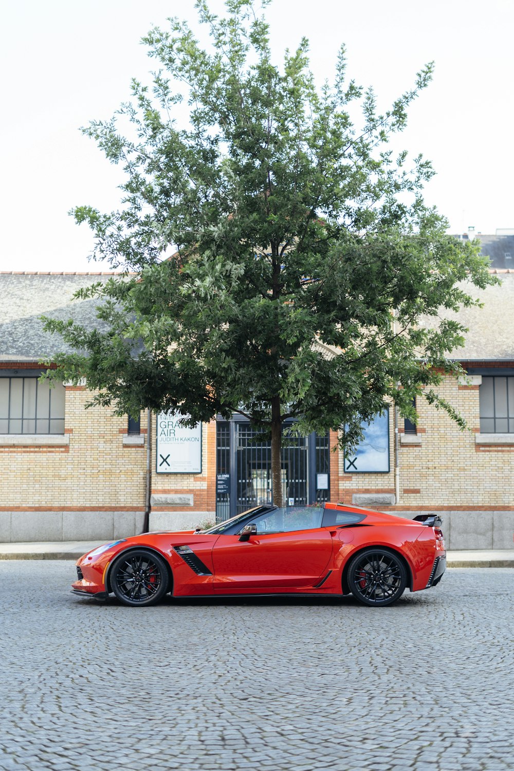 a red sports car parked in front of a tree